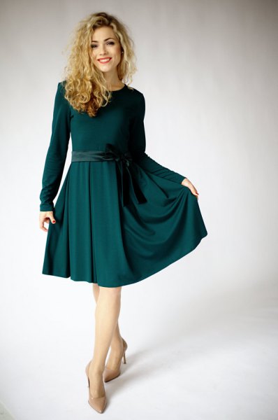 knälång, utsvängd klänning med ett mörkgrönt bälte och långa ärmar