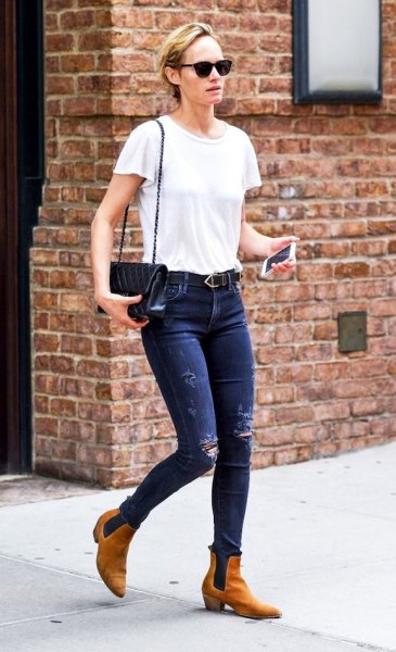 vit t-shirt med blå skinny jeans och bruna läderstövlar